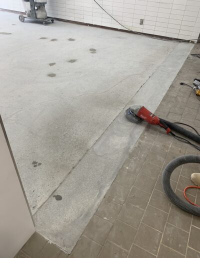 image shows a concrete floor being polished or ground by a floor grinder