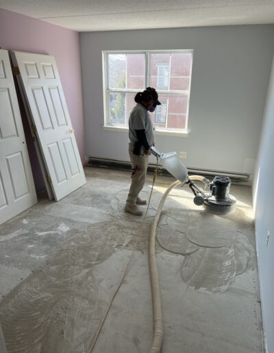 image shows a person operating a floor sanding machine in a room