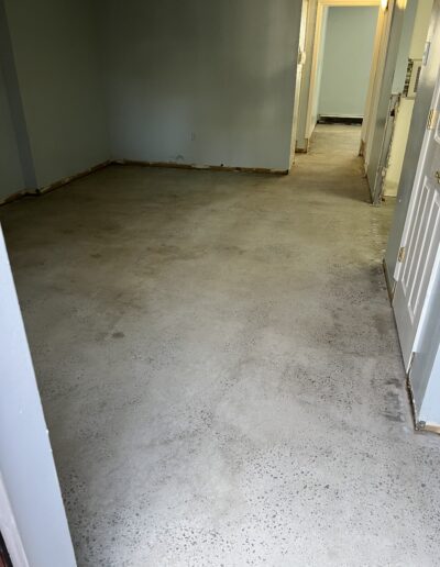 image shows a hallway or corridor with a concrete floor and light-colored walls