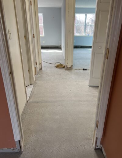 image shows a hallway with a concrete floor that appears to be in the process of being coated with an epoxy flooring system