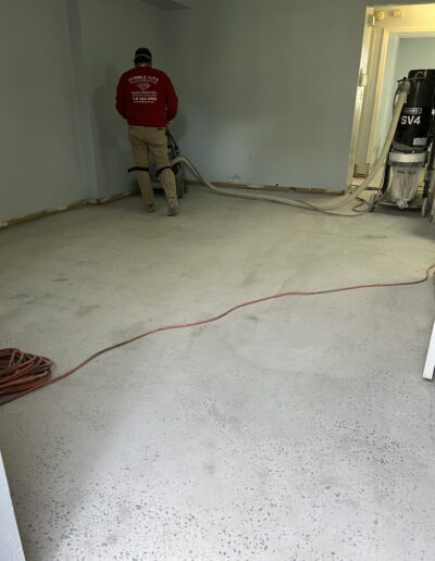 A man in a red t-shirt working on the floor, focused on completing the task