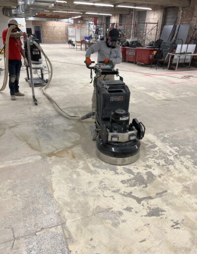 A man using a machine to smooth the floor, concentrating on achieving a polished surface